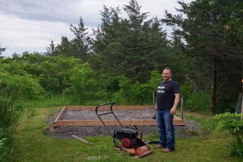 Jake standing next to the concrete form and gravel base with a plate tamper