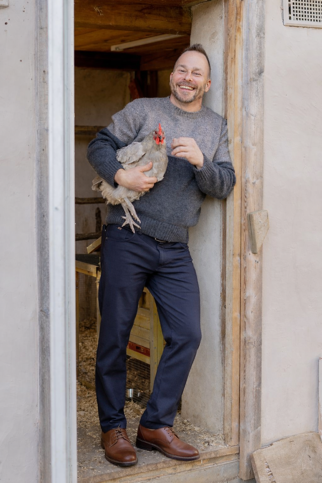 Jake Bergeron holding a chicken in his straw bale coop
